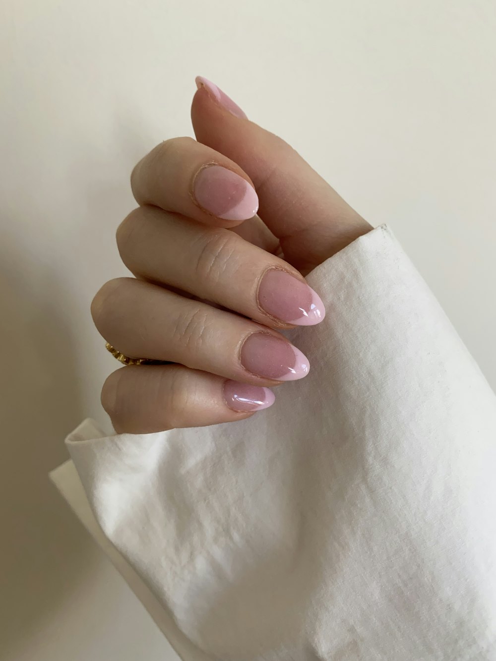 Hand with a pink manicure against white textile